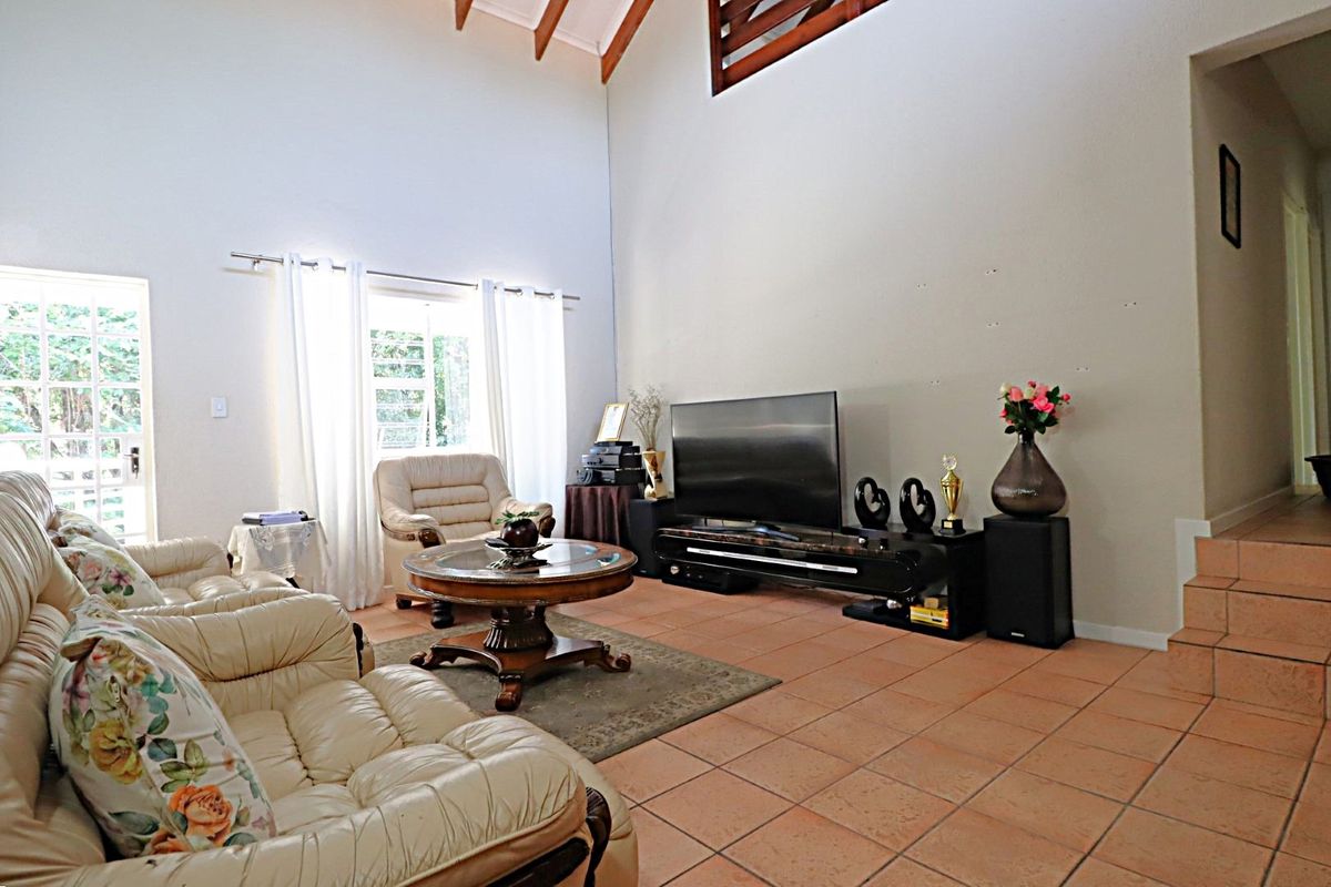 Spacious living room featuring high vaulted ceilings with exposed timber beams and terracotta floor tiles, offering a bright and airy atmosphere.