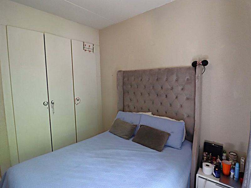 A functional bedroom featuring a built-in wardrobe with classic cabinetry, providing essential storage space within the room.