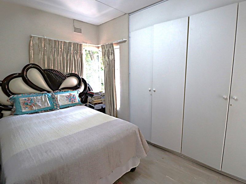 A bedroom featuring built-in cupboards and laminate flooring, providing functional storage and a neutral base for interior design.