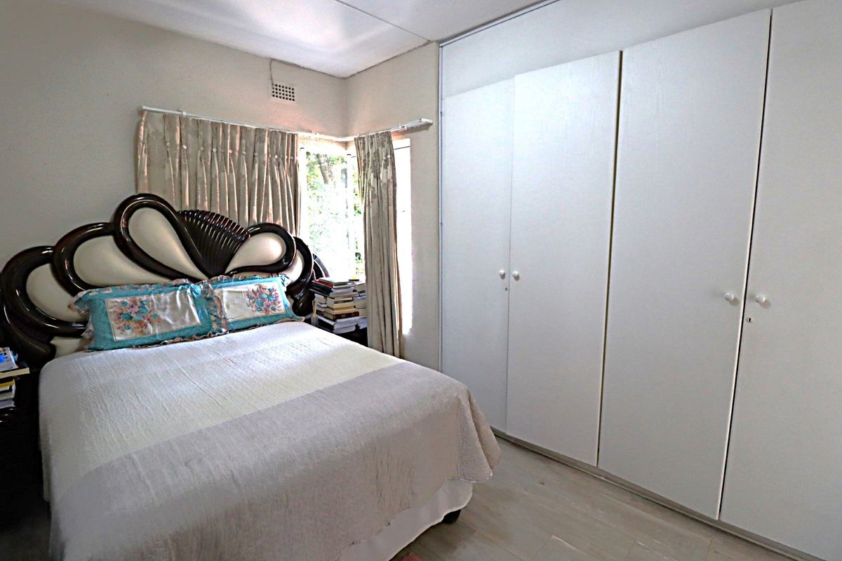 A bedroom featuring built-in cupboards and laminate flooring, providing functional storage and a neutral base for interior design.
