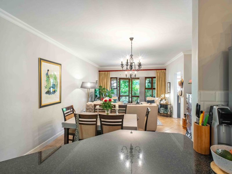 Open-plan living and dining area featuring tiled floors, elegant chandeliers, and sliding glass doors leading to an outdoor space.