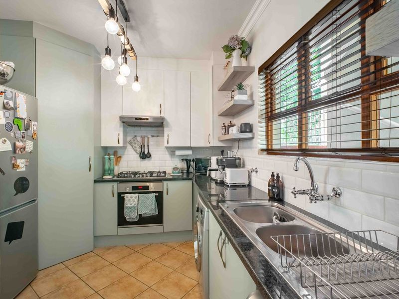 Modern kitchen featuring light cabinetry, granite countertops, subway tile backsplash, built-in oven with gas hob, and a double basin sink with window view.