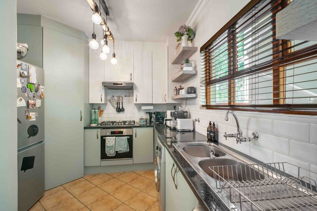 Modern kitchen featuring light cabinetry, granite countertops, subway tile backsplash, built-in oven with gas hob, and a double basin sink with window view.