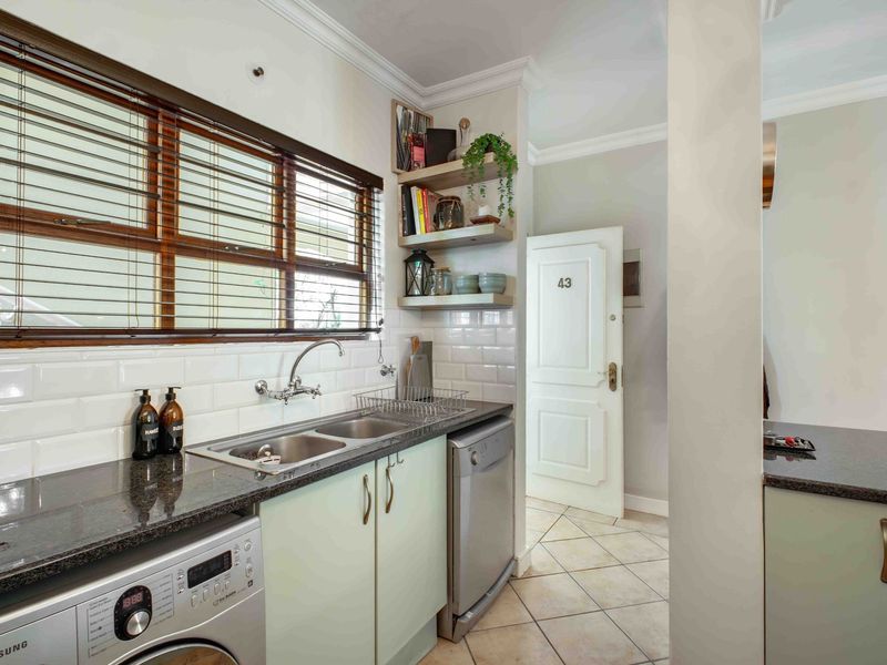 A well-maintained kitchen featuring granite countertops, a double basin sink, subway tile backsplash, and ample built-in cabinetry with tiled flooring.