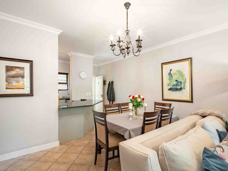 Open-plan living and dining area featuring tiled flooring, crown molding, and a granite breakfast bar connecting to the kitchen.