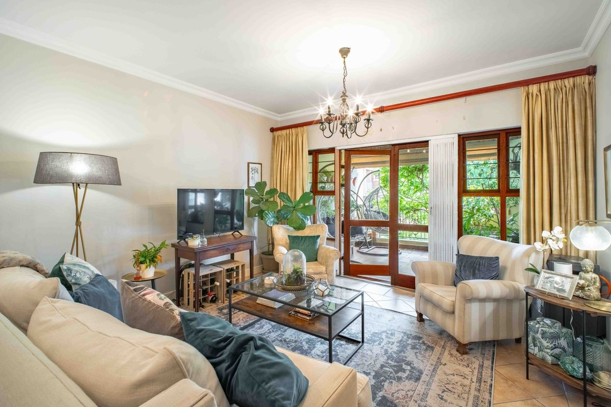A comfortable living room featuring tiled floors, crown molding, and large wooden sliding doors that provide access to an outdoor patio area.