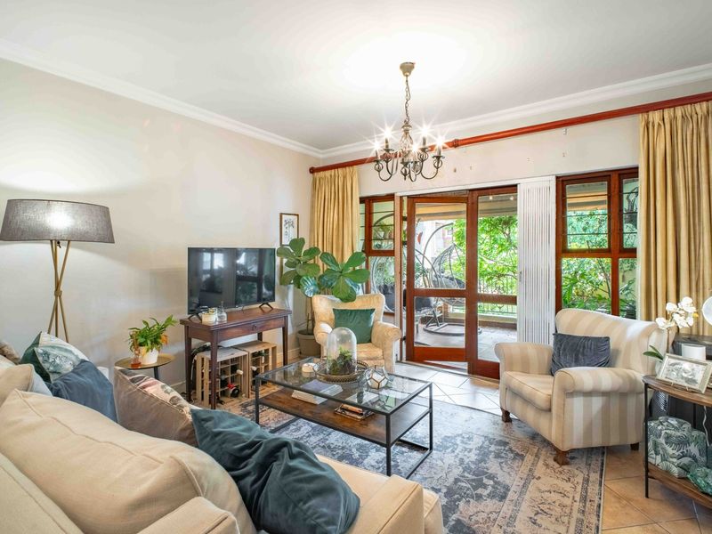 A comfortable living room featuring tiled floors, crown molding, and large wooden sliding doors that provide access to an outdoor patio area.