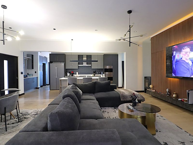 Modern open-plan living area featuring a sleek kitchen with built-in appliances, a central island, and a sophisticated lounge with a feature wall and fireplace.