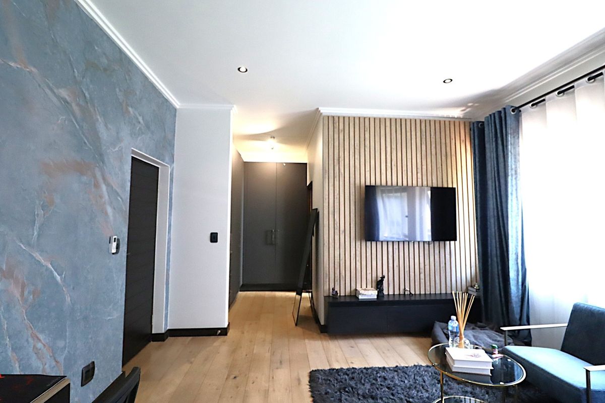 Modern living room featuring a stylish timber slat feature wall, recessed downlights, and high-quality engineered timber flooring with integrated storage cabinetry.