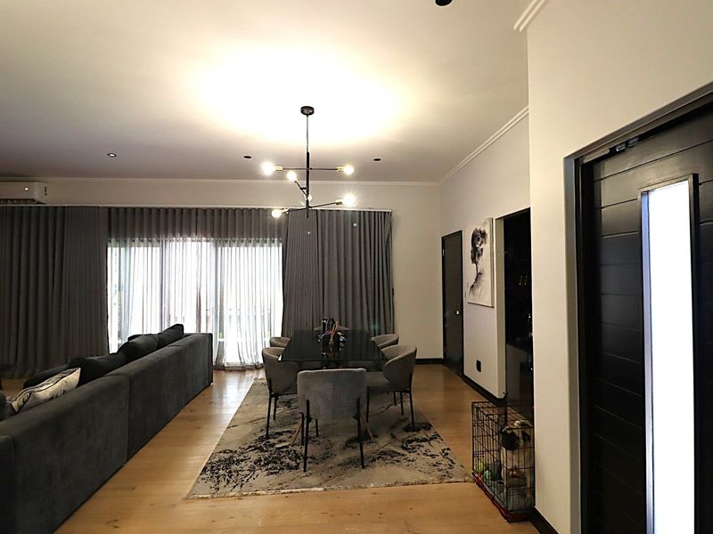 Spacious open-plan living and dining area featuring hardwood flooring, modern lighting, and large sliding glass doors leading to the exterior.