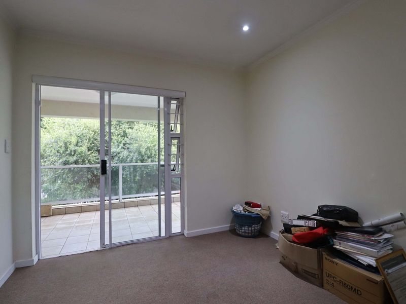 A vacant bedroom featuring neutral walls, carpet flooring, and a sliding glass door providing access to an outdoor balcony area.