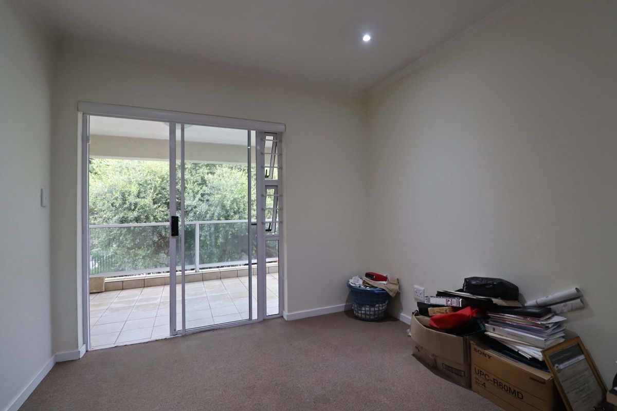 A vacant bedroom featuring neutral walls, carpet flooring, and a sliding glass door providing access to an outdoor balcony area.