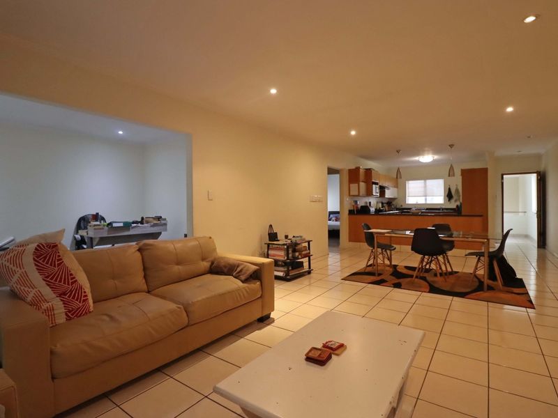 Spacious open-plan living and dining area featuring tiled flooring, recessed lighting, and a functional kitchen with built-in cabinetry.