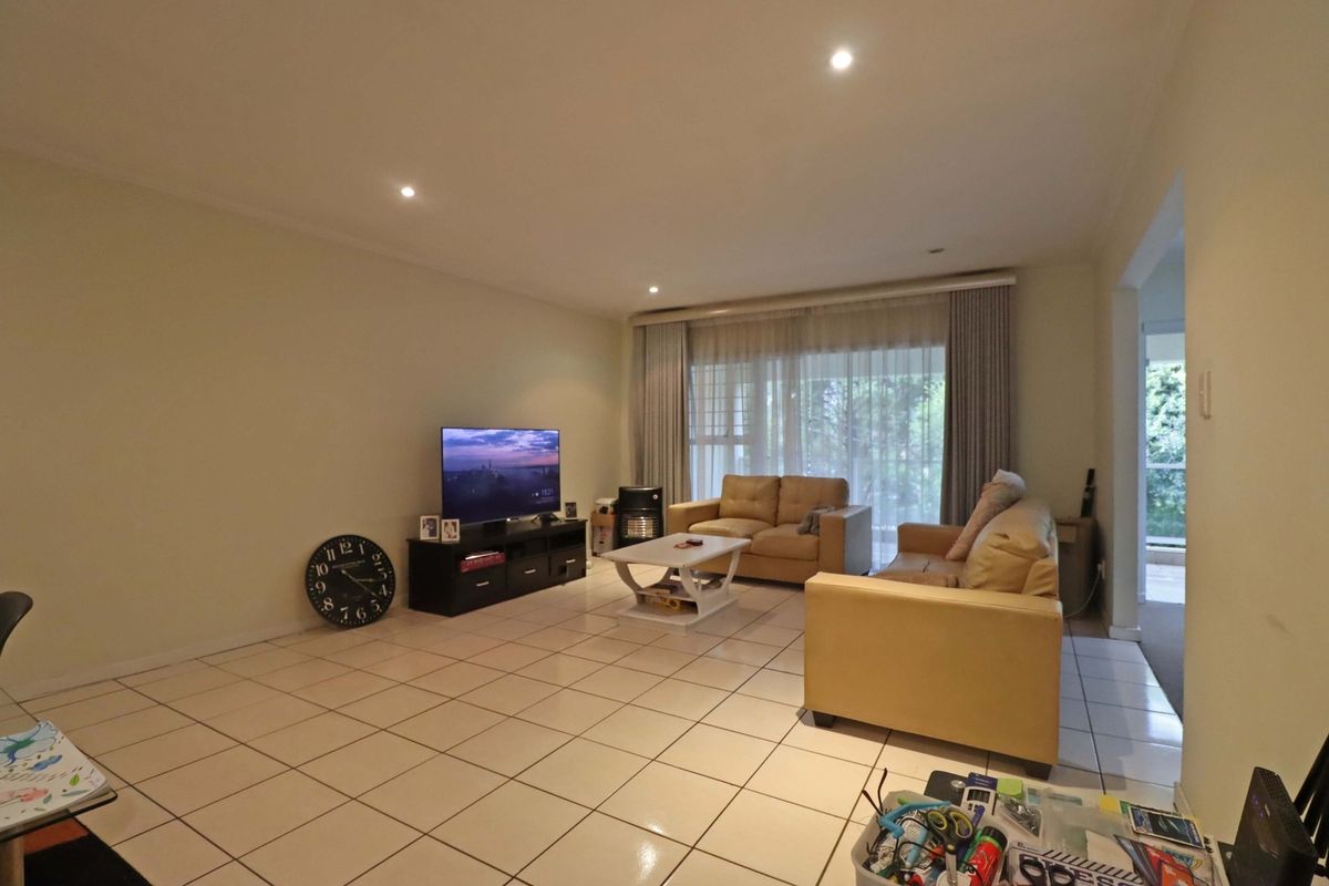 Spacious living room featuring neutral ceramic floor tiles, recessed downlighting, and large sliding glass doors providing access to the outdoor area.
