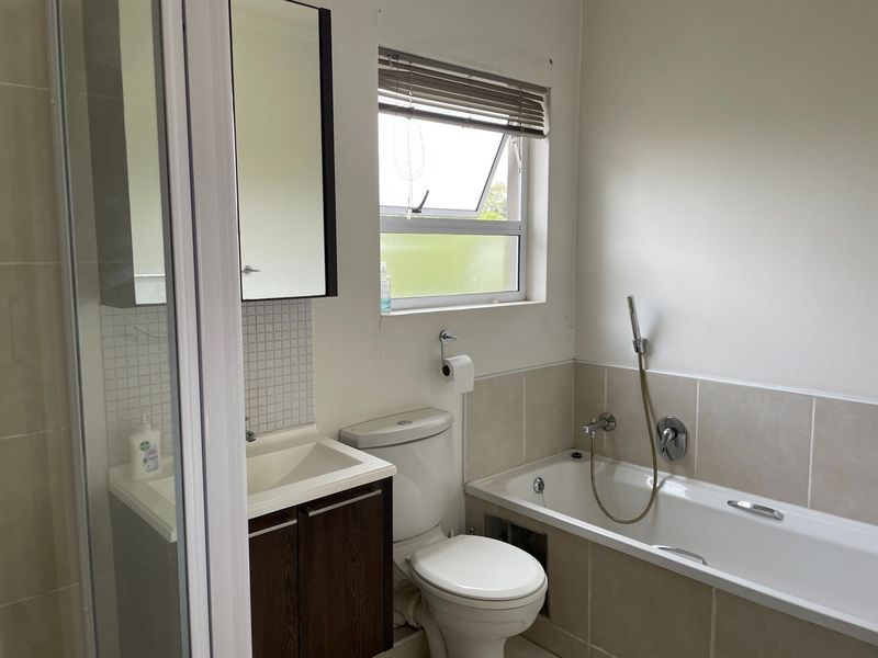 A functional bathroom featuring a shower enclosure, bathtub with handheld mixer, vanity cabinet with basin, and a toilet.