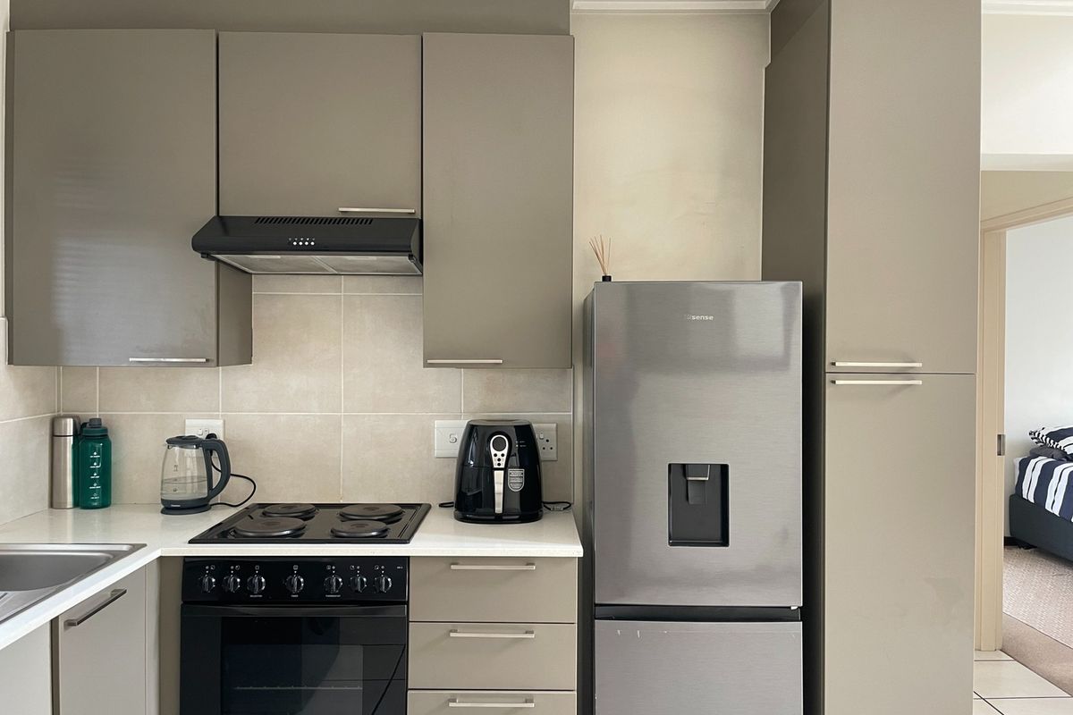 Modern kitchen featuring sleek grey cabinetry, built-in oven and hob, extractor fan, and tiled splashback with ample counter space.
