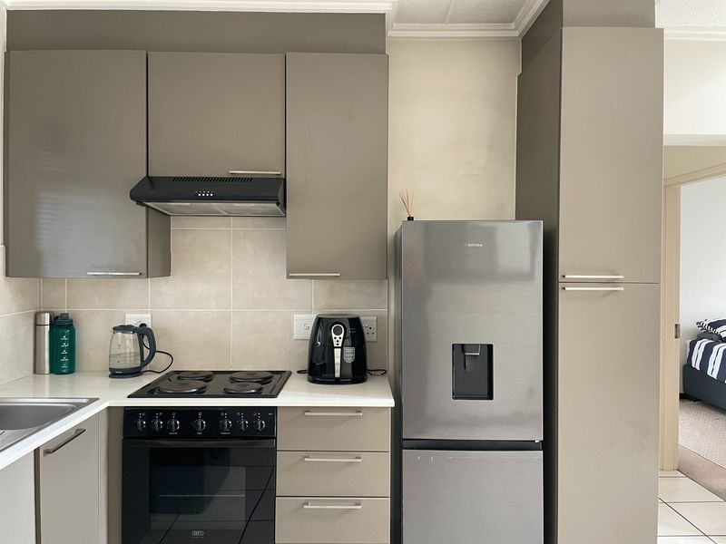 Modern kitchen featuring sleek grey cabinetry, built-in oven and hob, extractor fan, and tiled splashback with ample counter space.