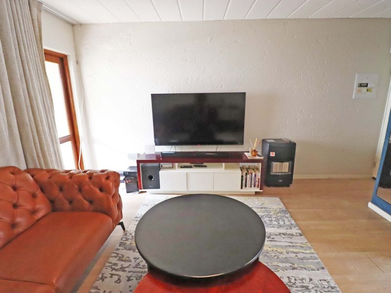 A comfortable living room featuring laminate flooring and textured walls, providing a functional space for relaxation and entertainment.