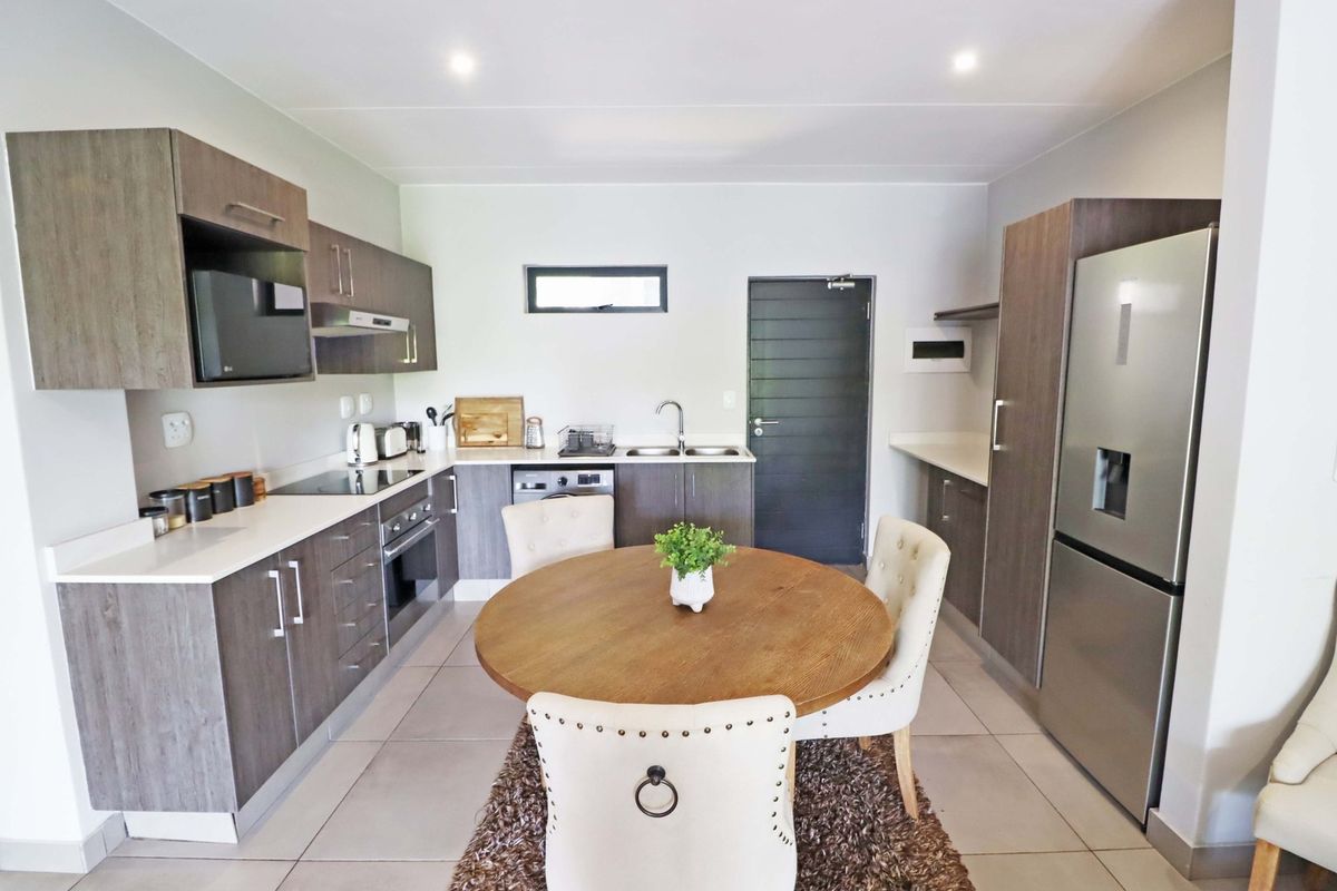 Modern kitchen featuring wood-finish cabinetry, stone countertops, integrated appliances, and a functional layout with tiled flooring and recessed lighting.