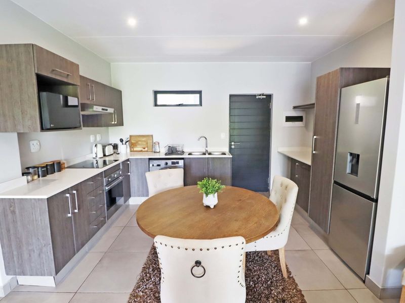 Modern kitchen featuring wood-finish cabinetry, stone countertops, integrated appliances, and a functional layout with tiled flooring and recessed lighting.