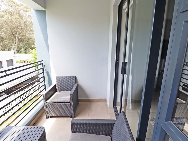 A covered balcony featuring tiled flooring, a metal balustrade, and large sliding glass doors providing access to the interior living space.