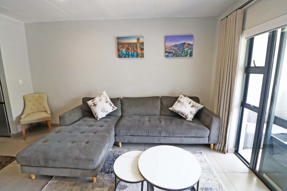 A well-maintained living room featuring neutral tiled flooring and a large sliding glass door providing natural light and access to the outdoor area.