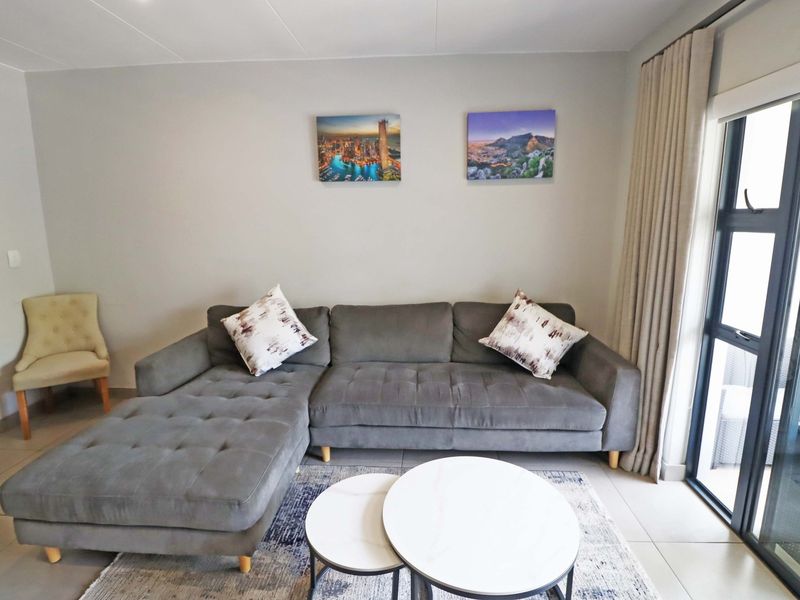 A well-maintained living room featuring neutral tiled flooring and a large sliding glass door providing natural light and access to the outdoor area.
