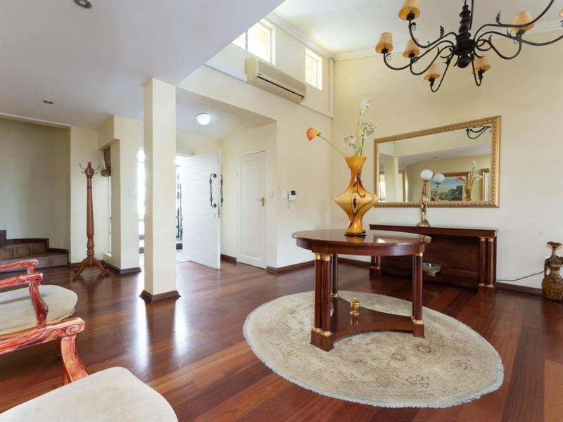 Spacious entrance hall featuring rich hardwood flooring, high ceilings with a skylight, and a welcoming open-plan layout.