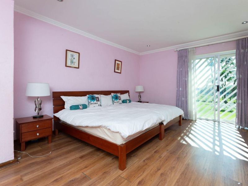 Spacious bedroom featuring laminate flooring, recessed lighting, and a sliding glass door providing natural light and access to the exterior.