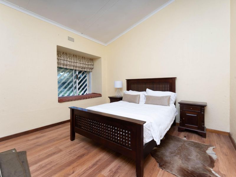 A bedroom featuring laminate flooring, a recessed window with security bars, and coved ceiling detailing.