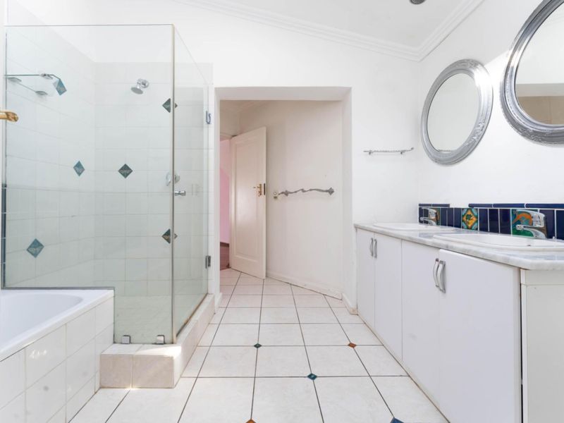 A functional bathroom featuring a glass-enclosed shower, a built-in bathtub, and a double vanity with white cabinetry.