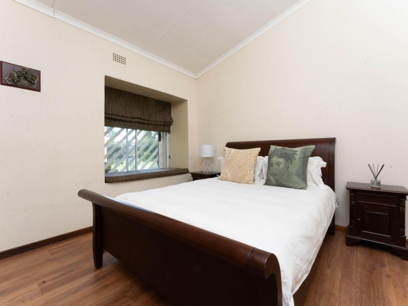 A bedroom featuring laminate flooring, a recessed window seat with security bars, and coving.