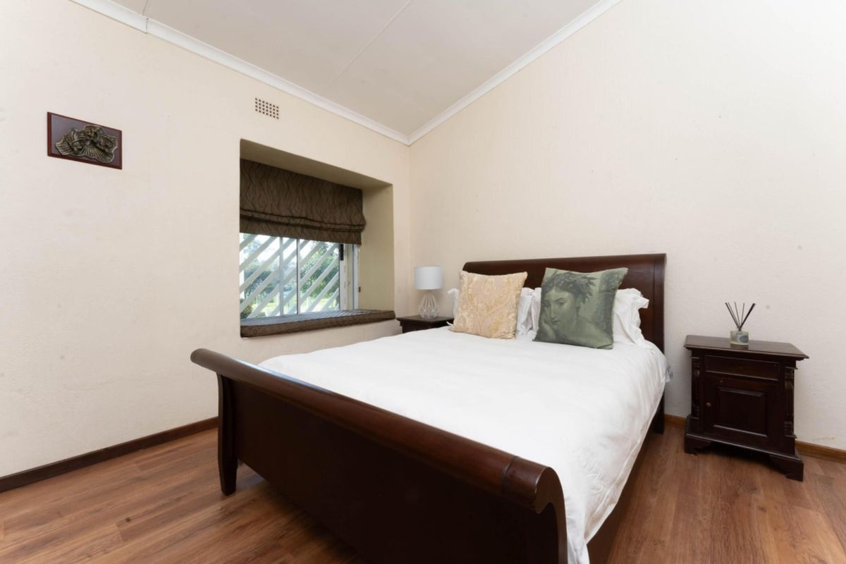 A bedroom featuring laminate flooring, a recessed window seat with security bars, and coving.