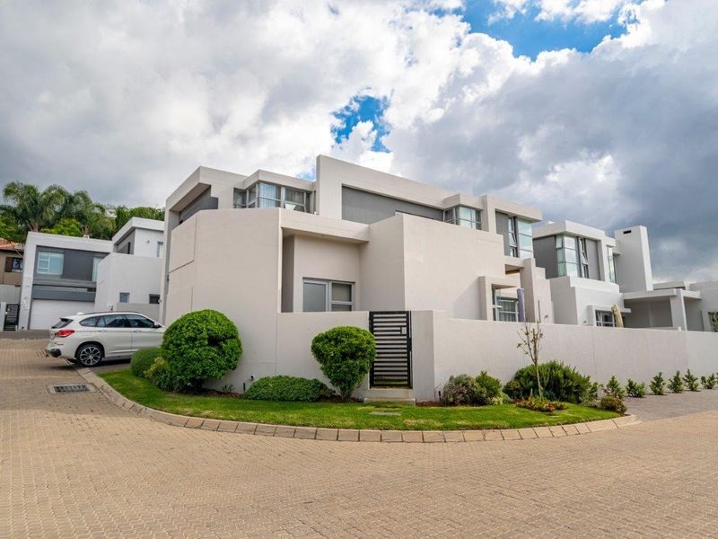 Modern townhouse exterior featuring a contemporary architectural design, paved driveway, and secure boundary wall with a pedestrian gate.