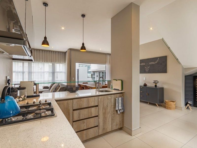 Modern open-plan kitchen featuring stone countertops, gas hob, and sleek cabinetry, flowing seamlessly into the living and dining areas with contemporary finishes.