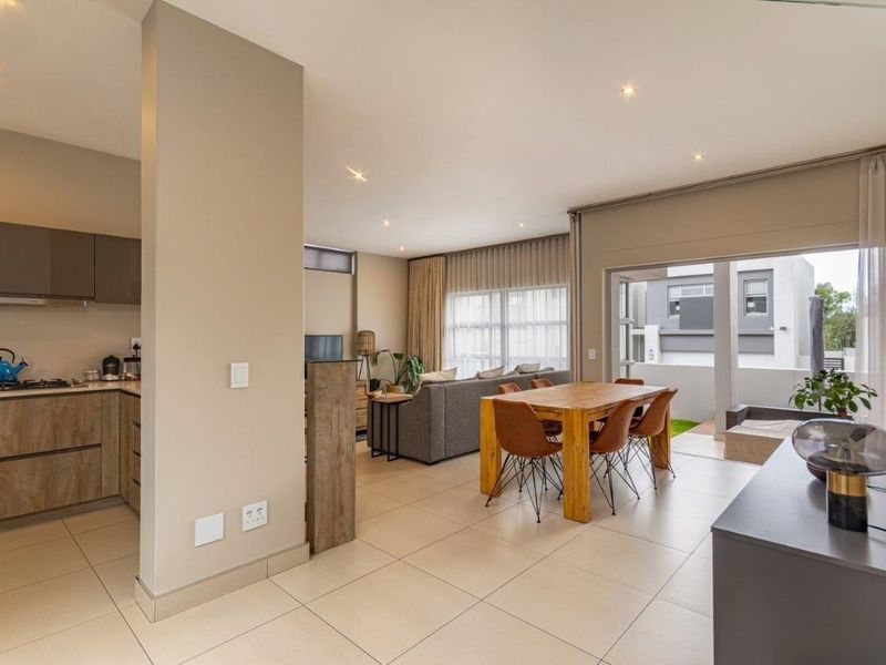 Spacious open-plan living and dining area featuring modern tiled floors, recessed lighting, and seamless flow to an outdoor patio through large sliding doors.