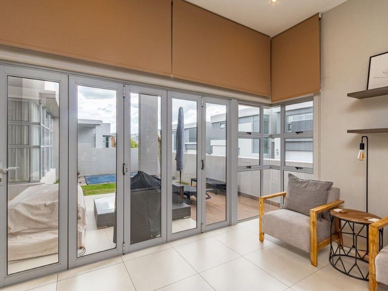 Bright living area featuring large aluminium stacker doors that provide seamless access to the outdoor patio and garden area.