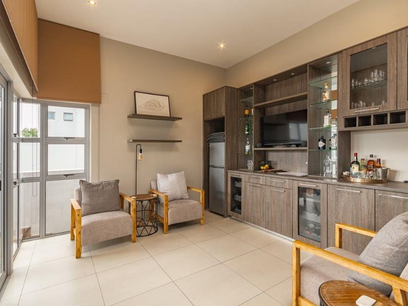 A modern living area featuring custom built-in cabinetry with integrated wine storage, tiled flooring, and large sliding glass doors leading to an outdoor space.