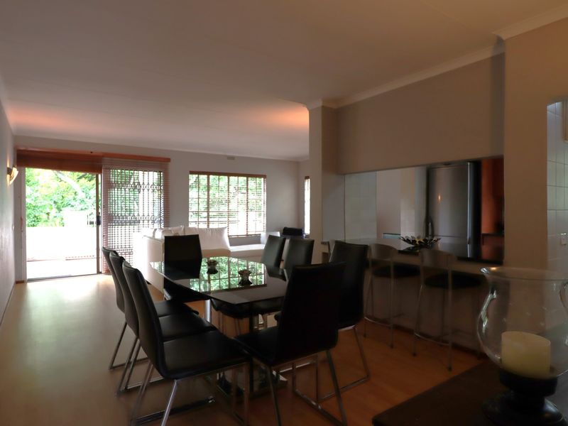 Open-plan living and dining area featuring laminate flooring, a breakfast bar, and sliding door access to the exterior.