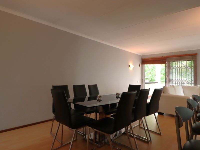 Open plan living and dining area featuring light laminate flooring, neutral walls, and a sliding glass door leading to an outdoor space.