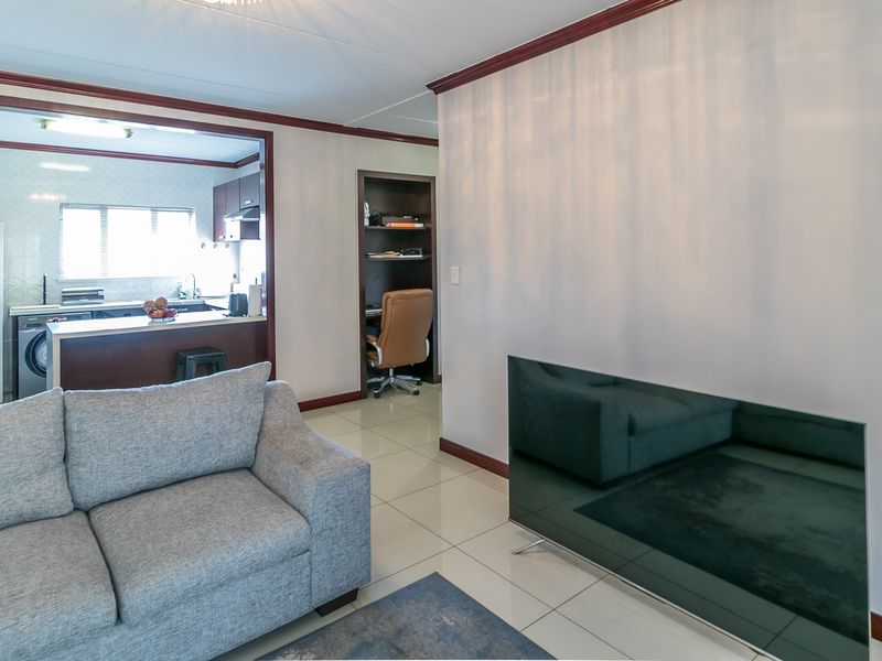 Open plan living area featuring tiled floors, crown molding, and a connected kitchen with built-in cabinetry and a breakfast island.