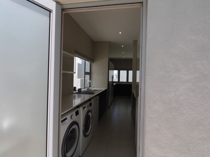 A functional scullery area featuring built-in cabinetry, a sink, and dedicated appliance connections, providing additional workspace and utility storage.