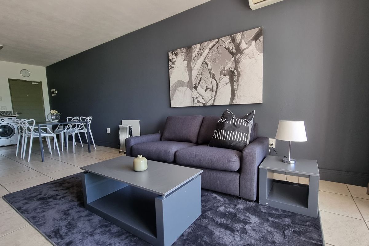 An open-plan living and dining area featuring tiled floors, a dark accent wall, and an integrated kitchen space.