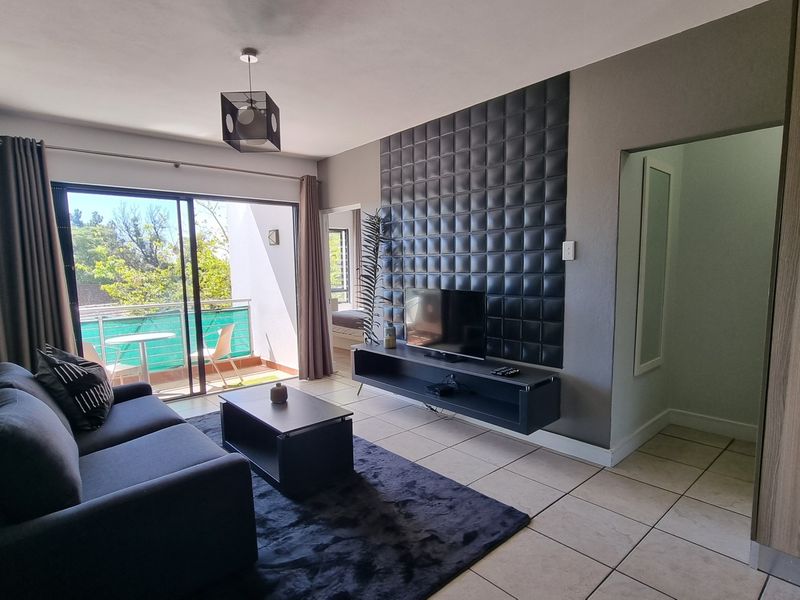 Modern living room featuring tiled floors, a decorative wall panel feature, floating media console, and direct access to a private balcony.