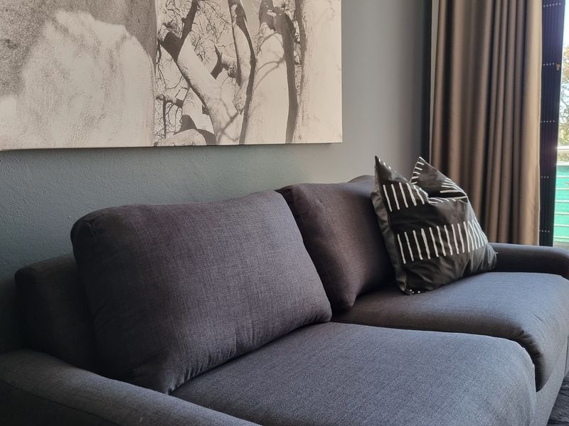 A modern living room area featuring dark grey walls and direct access to an outdoor balcony through a sliding glass door.