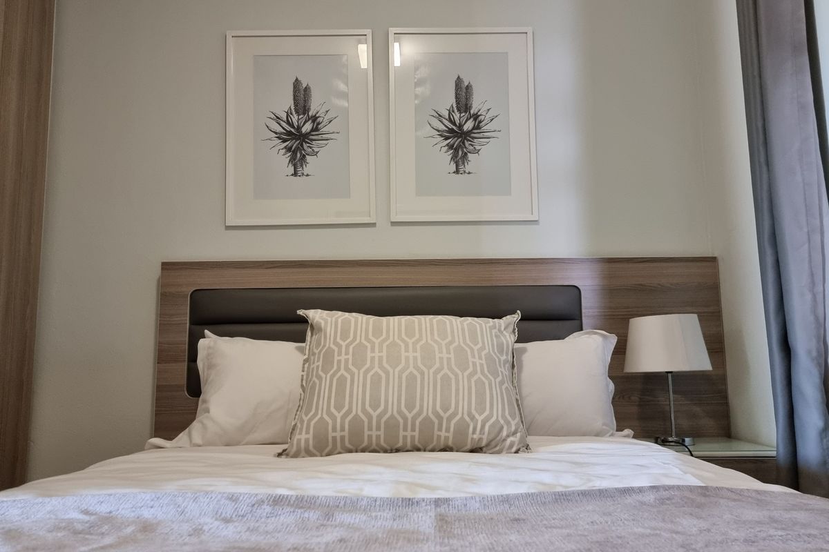 A well-maintained bedroom featuring a modern integrated headboard and built-in wardrobe storage.