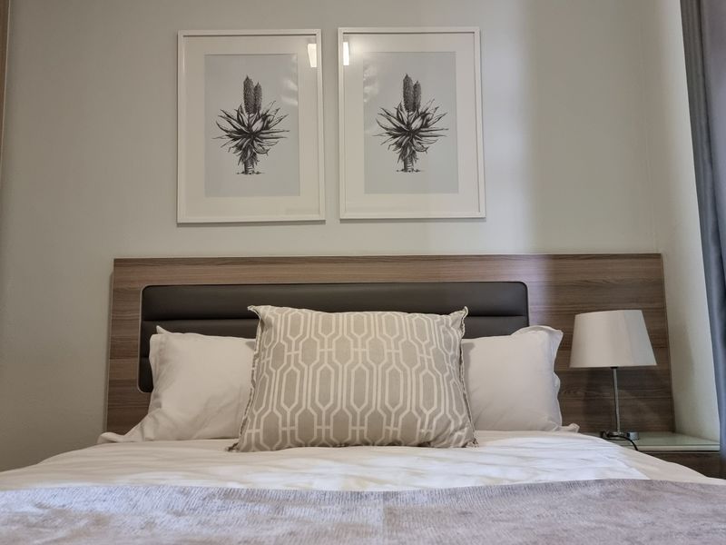 A well-maintained bedroom featuring a modern integrated headboard and built-in wardrobe storage.