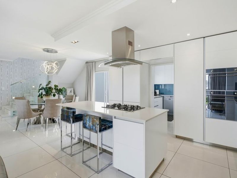 Modern open-plan kitchen featuring a central island with gas hob, sleek cabinetry, integrated appliances, and seamless flow into the adjacent dining area.