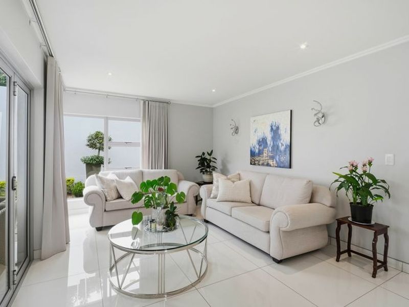 A bright and modern living room featuring polished tiled floors, recessed lighting, and large sliding glass doors that provide ample natural light.