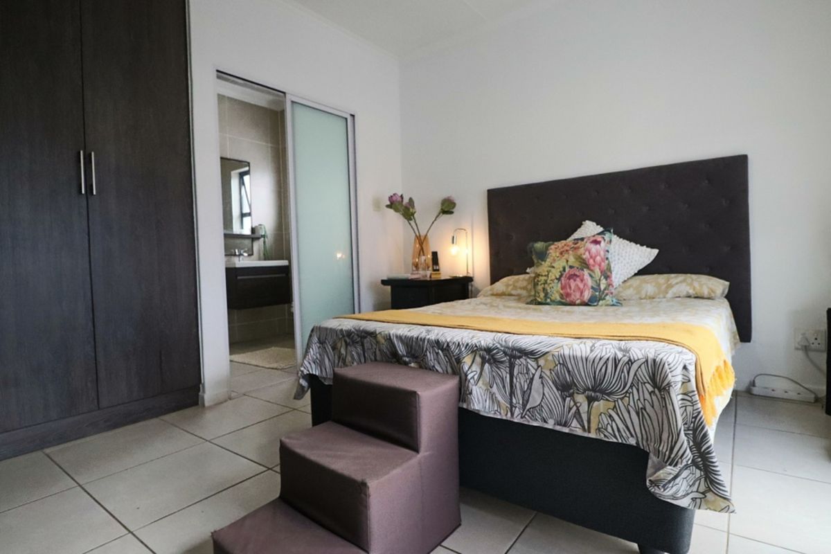 A well-maintained bedroom featuring tiled flooring, a large built-in wardrobe, and direct access to an en-suite bathroom through a sliding door.
